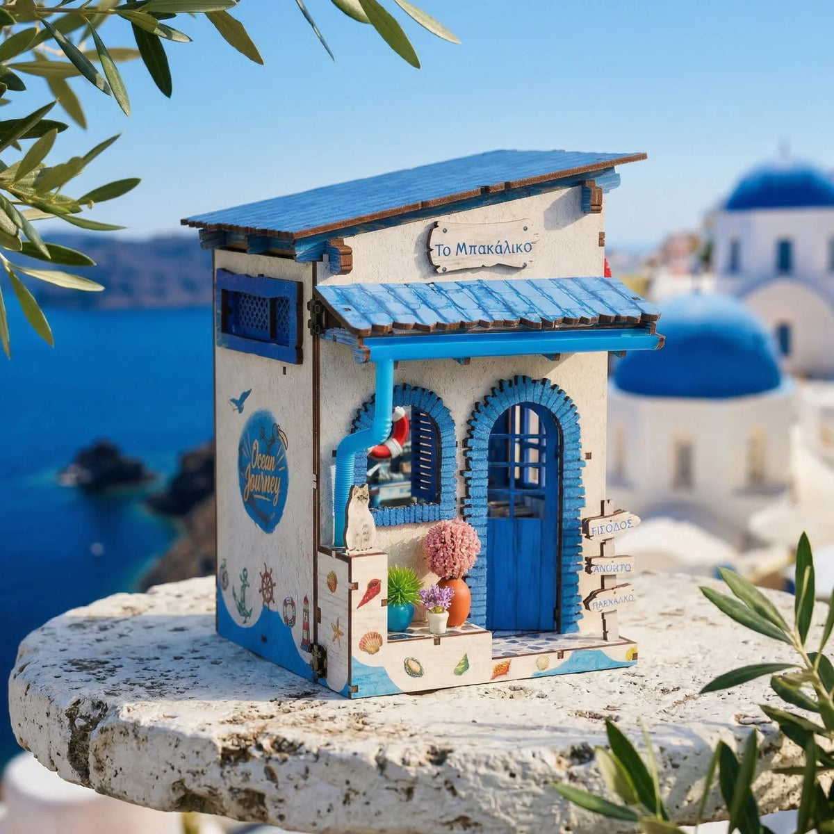 A wooden beach corner DIY book nook kit with blue and white accents sits on a stone surface.
