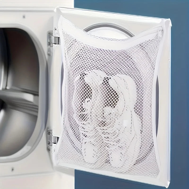 A white reusable mesh shoe wash bag is shown inside an open washing machine door.