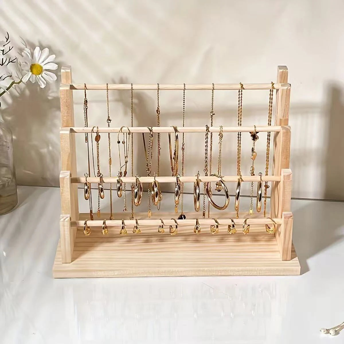 A solid wood ladder jewelry organizer displaying various gold-toned necklaces and earrings.