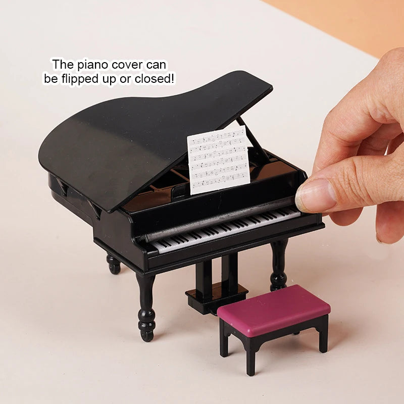 A black 1:12 scale dollhouse piano with a bench is shown, demonstrating that the cover can be flipped up or closed.