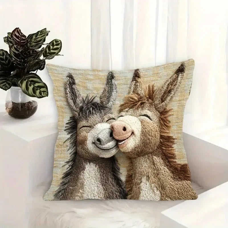 A beige and brown embroidered pillow featuring two adorable donkey faces.