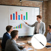 A young man points with a stainless steel telescopic teacher pointer at a bar chart displayed on a whiteboard in an office se