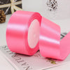 A roll of bright pink satin ribbon used for gift wrapping and DIY crafts.