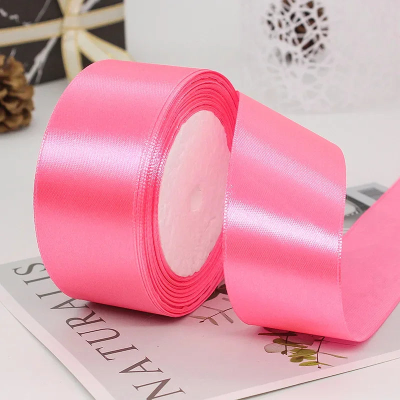 A roll of bright pink satin ribbon used for gift wrapping and DIY crafts.