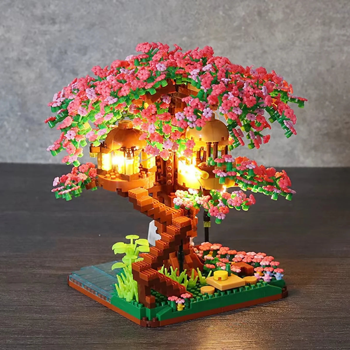 A miniature building block treehouse featuring pink blossoms and glowing lights.