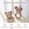 A handmade crochet bunny toy with a natural wood teether ring shown against a light background.