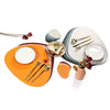 A set of reversible non-slip placemats and tableware featuring orange, gray, and white ceramic plates and cutlery.