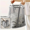A gray foldable mesh laundry basket with handles is shown being held by a hand.