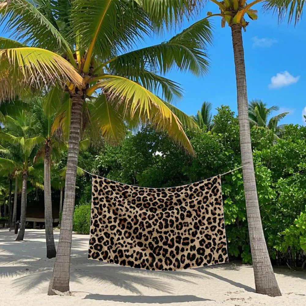 A leopard print towel is hanging between two palm trees in a tropical outdoor setting.