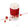 A spool of red nylon macramé cord with several loose strands displayed on a white background.
