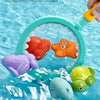 A hand holds a green plastic catch net filled with colorful floating bath toys including a turtle and a shark in clear water.