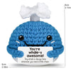 A blue crochet whale doll with a smiling face and a tag that reads You're whale-y awesome!
