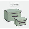 A set of two rectangular fabric storage boxes in a muted green color with dark trim.