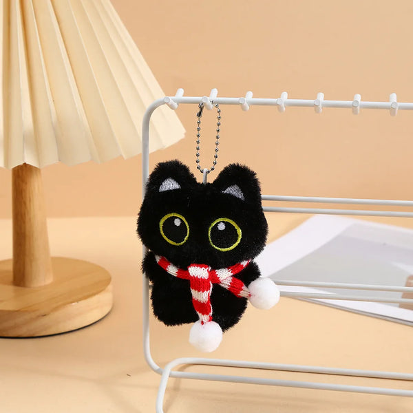 Un suave llavero de gato negro de peluche colgado en un soporte de alambre.