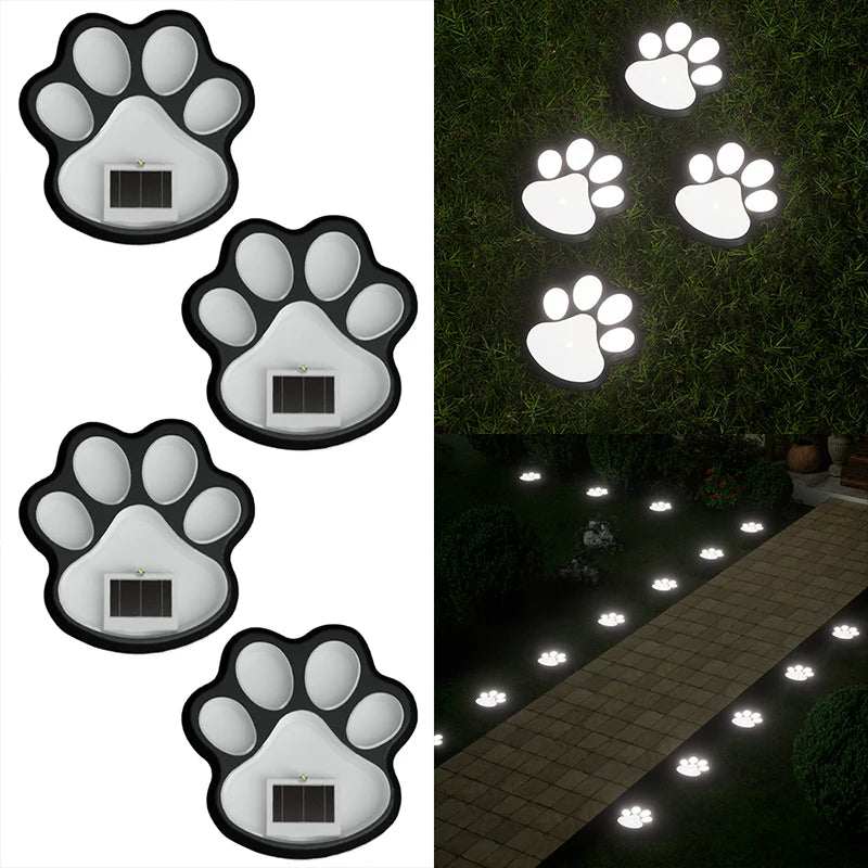 A set of four solar dog paw pathway lights illuminating a stone walkway in a garden.