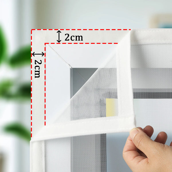 Gros plan d'un écran de fenêtre autocollant blanc en cours de mesure et d'installation dans un cadre de fenêtre.