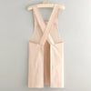 A light beige cotton kitchen apron with adjustable straps hanging on a wooden hanger.