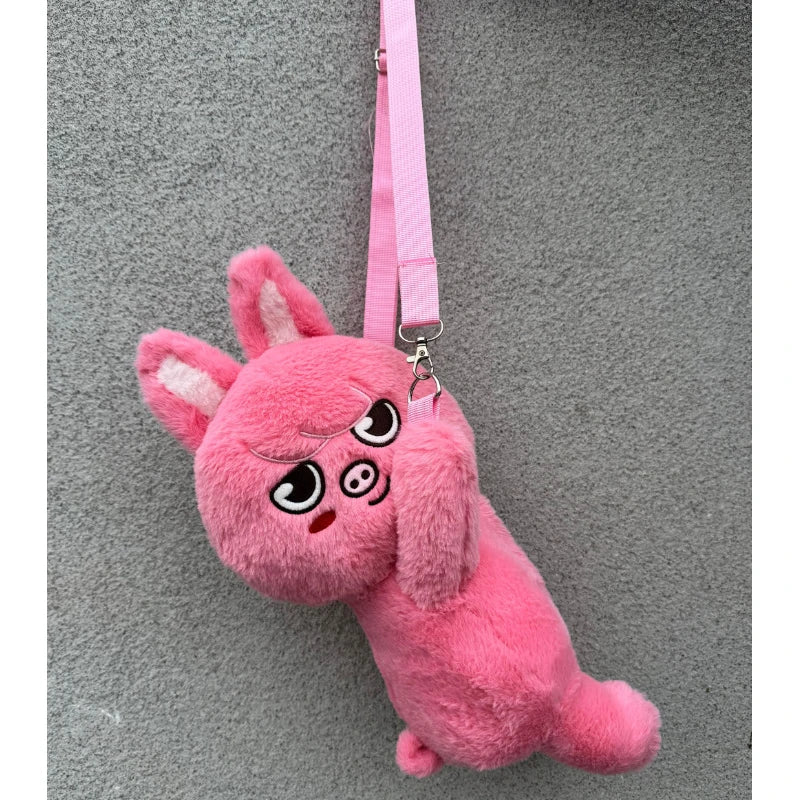 A pink, fluffy plush doll shaped like an animal with large ears and a stitched face, hanging from a pink strap.