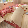 A pink and white cartoon embroidered duvet cover set displayed on a bed with plaid bedding.