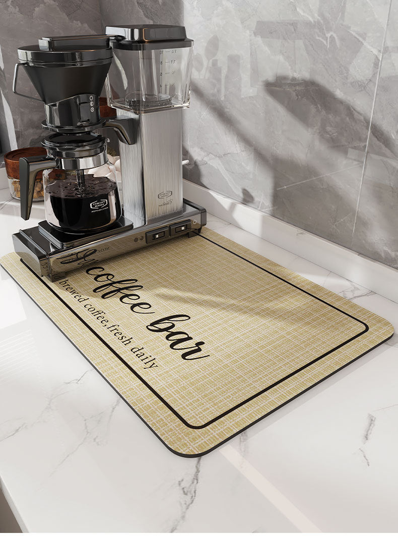 A silver coffee maker and a mat labeled brewed coffee fresh daily are displayed on a white marble surface.