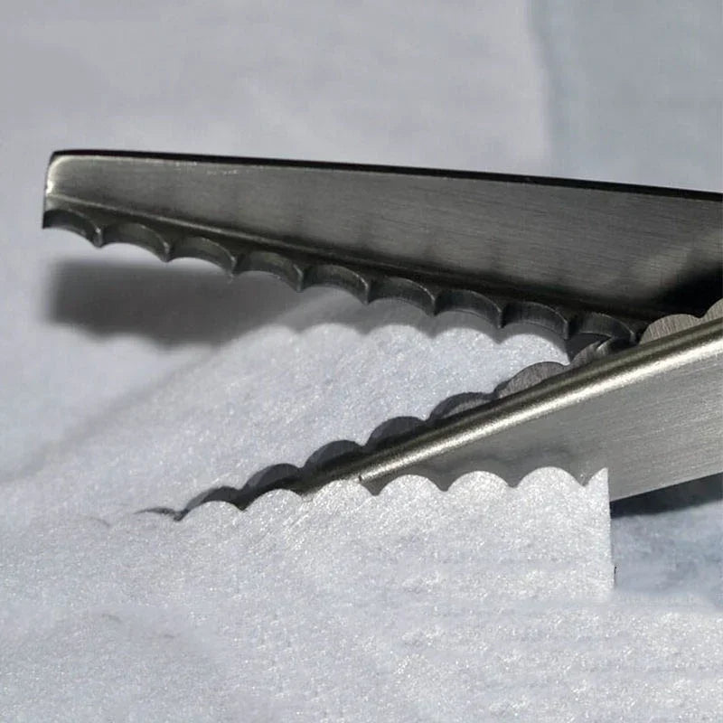 Close-up of professional scalloped pinking shears with sharp blades resting on white fabric.