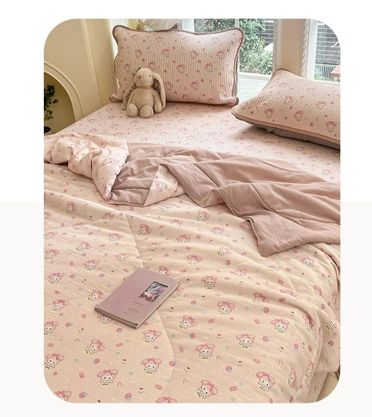 A light pink quilt featuring a cartoon pattern of small animals and flowers, displayed on a bed with a matching pillow.
