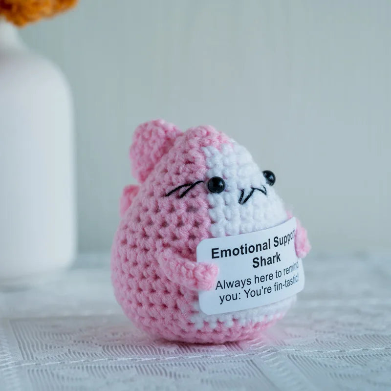 Handmade crochet doll resembling a pink and white striped shark with a sign for emotional support decor