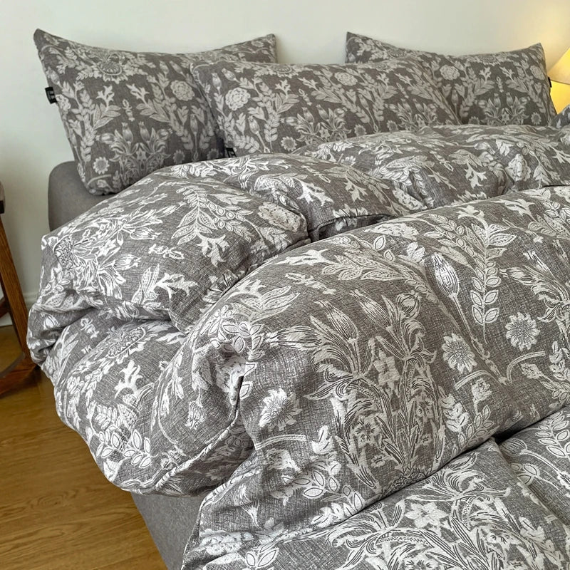 A set of soft printed duvet covers and pillowcases in gray and white floral patterns on a bed.