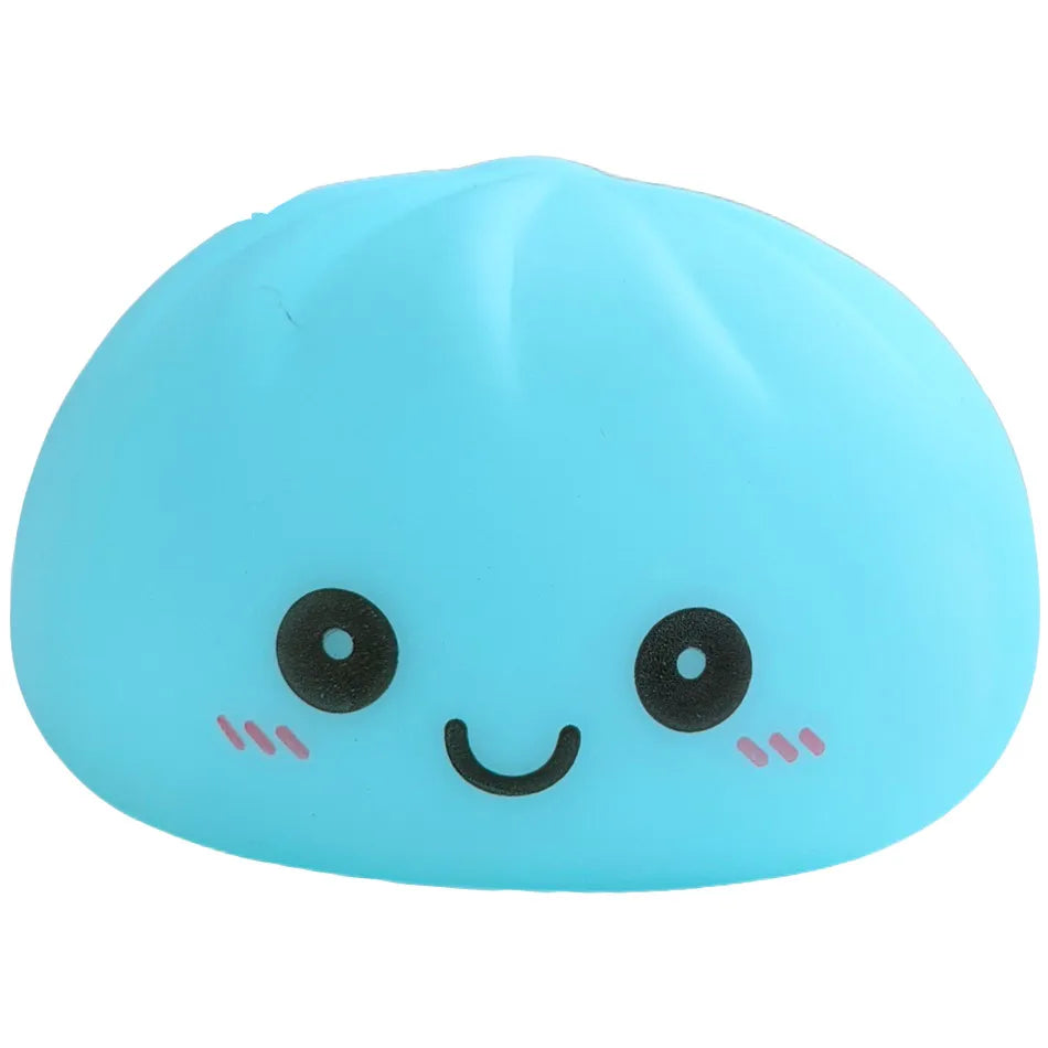 Juguete suave azul claro en forma de dumpling sonriente con ojos negros y mejillas rosadas.