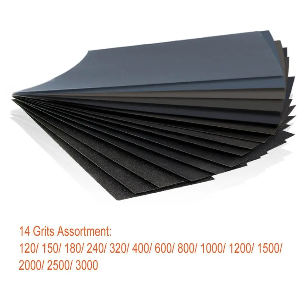 A fan of black sandpaper sheets with various grit sizes laid out on a white surface.
