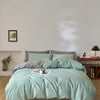 A light mint green quilted duvet cover set displayed on a bed with neutral bedding and wall art.