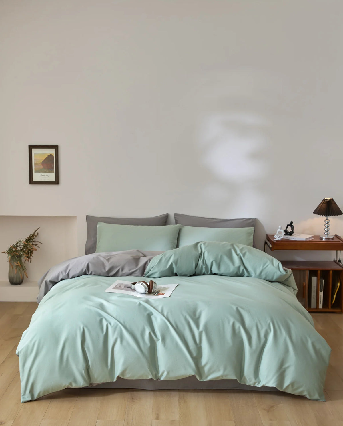 A light mint green quilted duvet cover set displayed on a bed with neutral bedding and wall art.