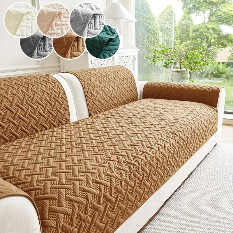 A tan quilted anti-slip sofa cushion is shown on a white sofa, with natural light and greenery in the background.