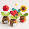 Handmade crochet plant decorations featuring red and yellow flowers with green leaves.