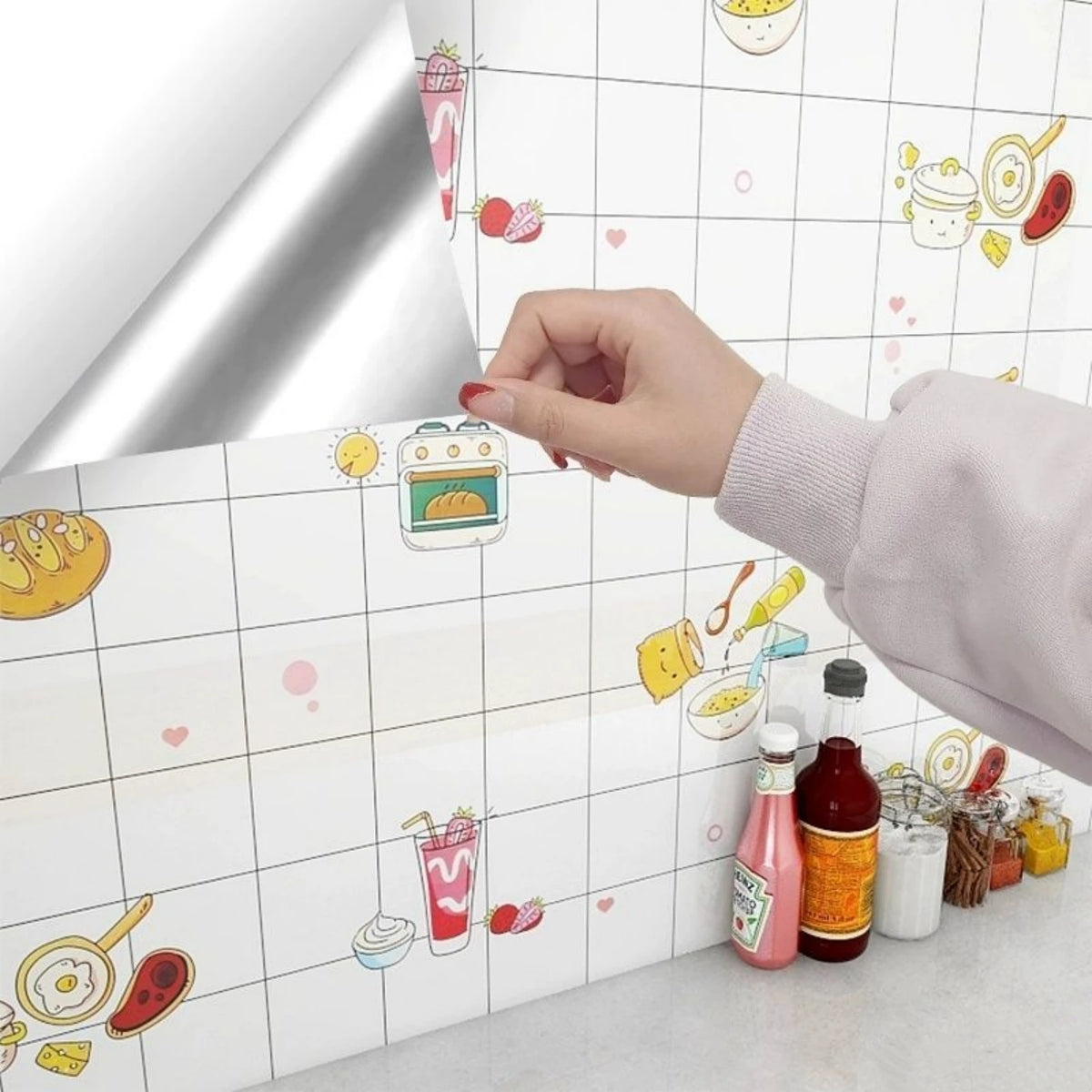 A hand is applying self-adhesive marble contact paper featuring colorful food illustrations onto a white surface.