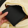 A hand is holding a black fabric pouch from a light yellow garment, showing the interior of the pouch.