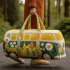 A person holds a quilted travel duffle bag with yellow and green fabric and floral embroidery in an outdoor setting.