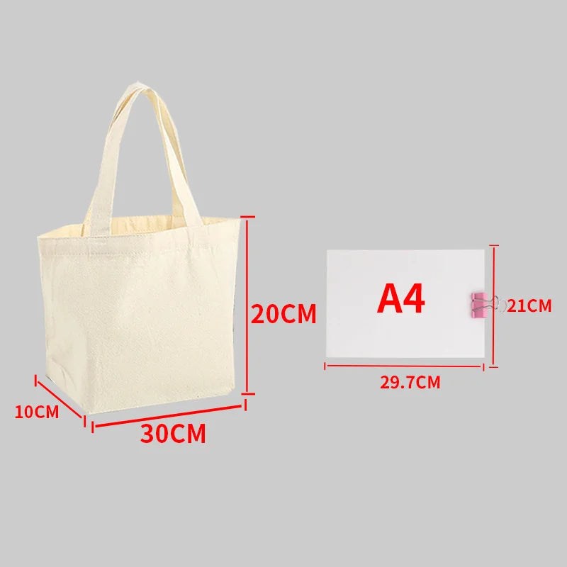 A beige canvas shopping tote bag shown next to an A4 sized white card for scale.