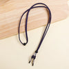 A dark navy blue adjustable lanyard for glasses is laid on a light wooden cutting board.