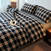 A plaid duvet cover in navy and beige tones is displayed on a bed with a wooden side table.