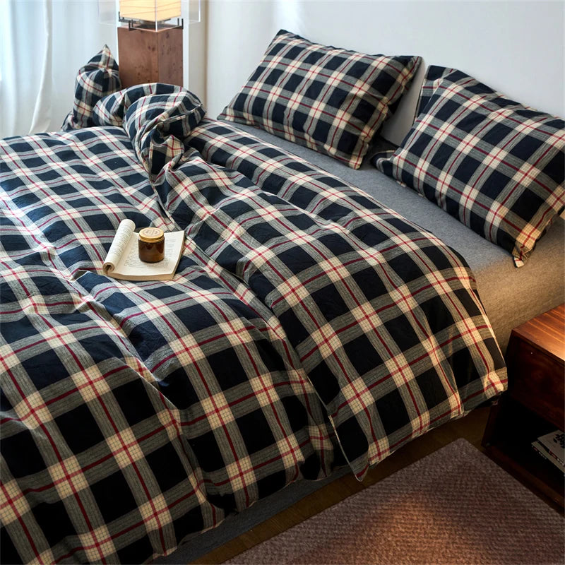 A plaid duvet cover in navy and beige tones is displayed on a bed with a wooden side table.
