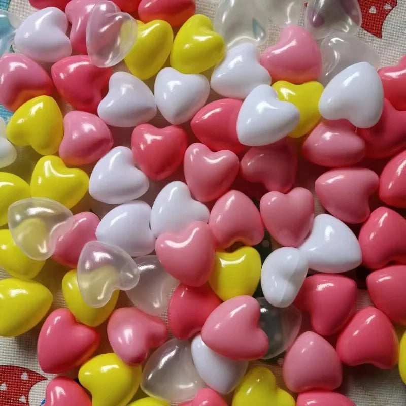 A close-up of a 50 pack of colorful non-toxic ball pit balls in pink, yellow, and white heart shapes.