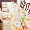 A long table set for a party featuring white and yellow daisy flower themed disposable tableware.