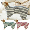A fluffy dog wearing a striped, quick-dry bathrobe in gray and white, standing on a light surface.