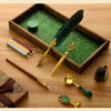 A vintage calligraphy fountain pen set with a wax seal stamp kit displayed in a wooden box on a wooden surface.