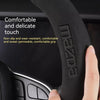 A hand grips a black steering wheel cover, highlighting its comfortable and delicate touch features.