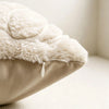 A close-up of a beige plush throw pillow cover with fluffy cream-colored faux fur trim.