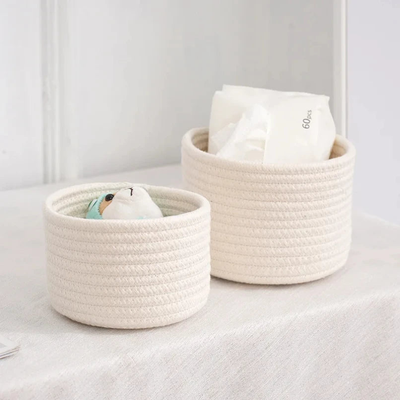 A beige handwoven cotton rope storage basket filled with white tissue paper, used for desk organization.
