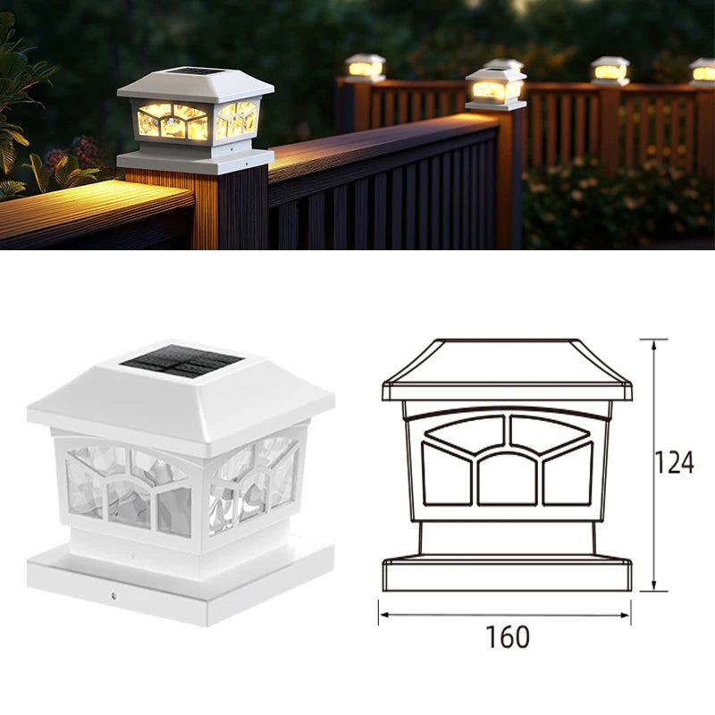 A white solar post cap light fixture with a glass enclosure mounted on a wooden fence or deck.