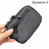 A hand holds a black Dyneema 3 utility pouch featuring a subtle plaid pattern and zippered closure.